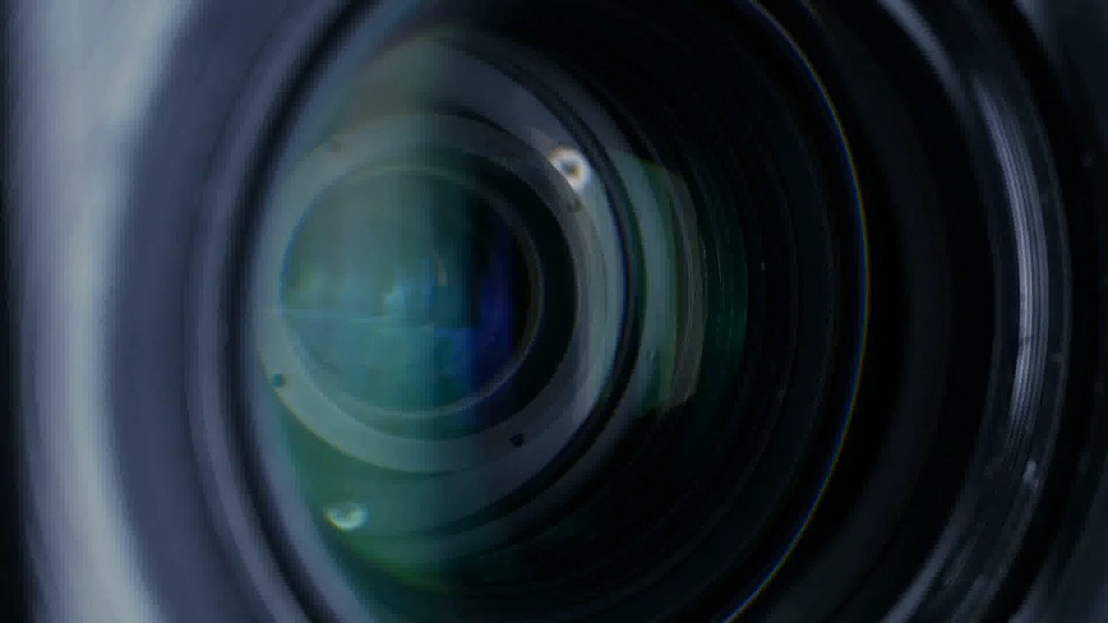 Close-up of a camera lens with blue and green reflections. Still from the YourLegend showreel.