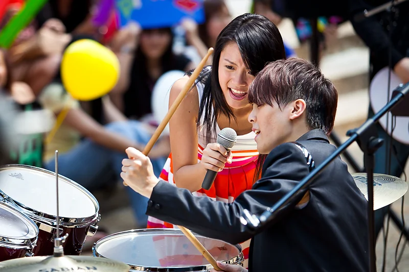 A singer leans in to a drummer during a live show.